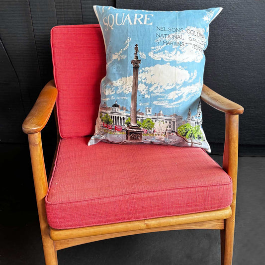 Decorative tea towel pillow with a design of Trafalgar Square, Nelson's Column and surrounding buildings with blue sky, on mcm chair