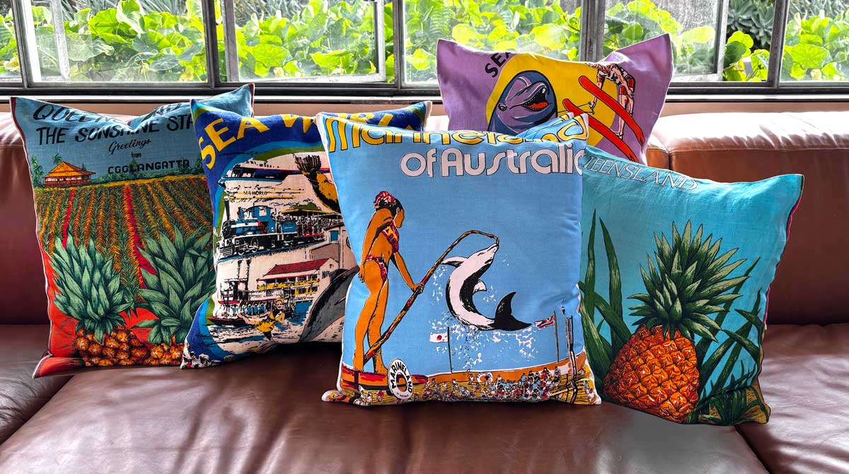 Queensland souvenir teatowel cushion covers on tan leather sofa