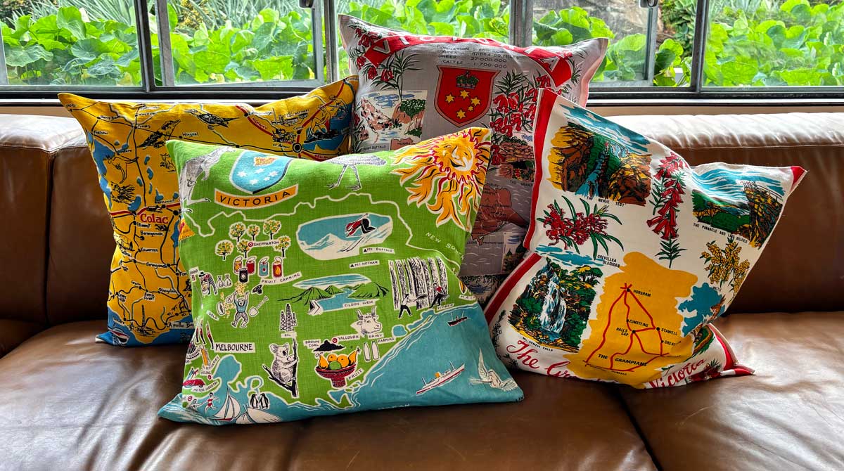 Victoria souvenir teatowel cushion covers on tan leather couch