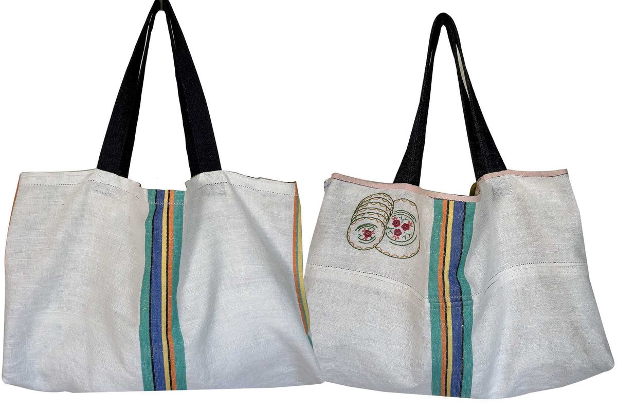 Tote bag made from antique linen teatowel with a hand-embroidered design of saucers, featuring denim handles.